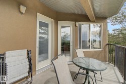 Private balcony with textured exterior finish, featuring two glass-paned doors, a sliding window, and a dark metal railing - 