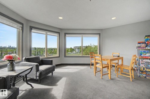 Spacious room featuring multiple large windows with grey trim, recessed lighting, and grey carpeting - 303 530 Hooke Road, Edmonton, AB - Indoor Photo Showing Living Room