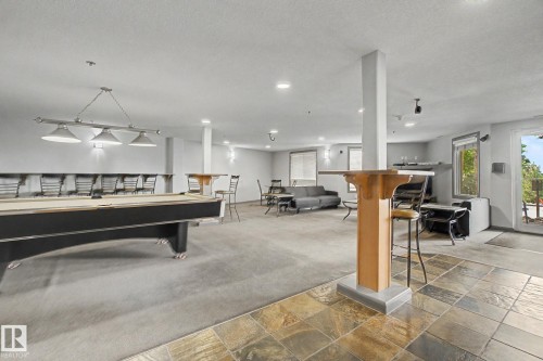 Spacious entertainment area featuring a full-size billiard table, recessed lighting, and a mix of carpet and natural stone tile flooring - 303 530 Hooke Road, Edmonton, AB - Indoor Photo Showing Other Room