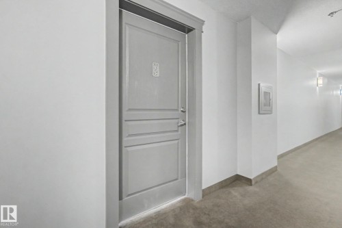 Entry door with paneled detailing, chrome hardware, and a number plate - 303 530 Hooke Road, Edmonton, AB - Indoor Photo Showing Other Room