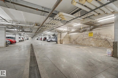 Underground parking garage featuring concrete flooring, overhead fluorescent lighting, and visible ceiling conduit - 303 530 Hooke Road, Edmonton, AB - Indoor Photo Showing Garage