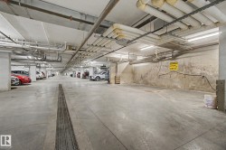 Underground parking garage featuring concrete flooring, overhead fluorescent lighting, and visible ceiling conduit - 