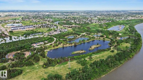Aerial perspective showcasing a sprawling parkland with multiple lakes, dense tree coverage, and open grassy areas - 303 530 Hooke Road, Edmonton, AB - Outdoor With Body Of Water With View