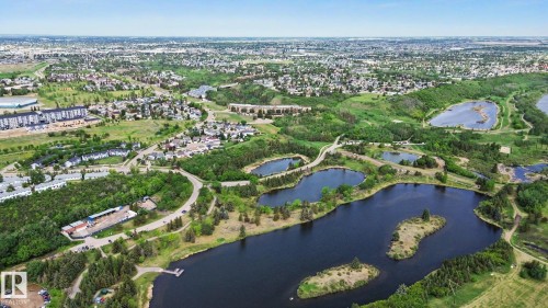 Expansive aerial perspective showcasing a residential community surrounded by natural landscapes - 303 530 Hooke Road, Edmonton, AB - Outdoor With Body Of Water With View