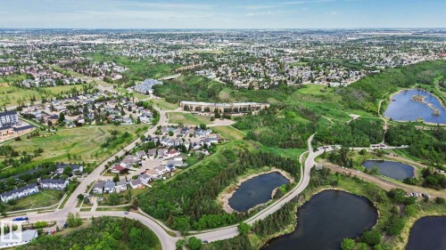 Aerial perspective showcasing a residential area with varied housing types, extensive green spaces, and multiple bodies of water - 303 530 Hooke Road, Edmonton, AB - Outdoor With View