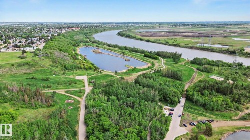 Expansive natural landscape featuring a winding river, a smaller body of water, extensive green spaces, and dense tree cover - 303 530 Hooke Road, Edmonton, AB - Outdoor With View