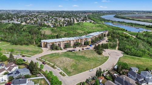 Multi-story residential building featuring a light-colored facade with balconies, surrounded by expansive green spaces and mature trees - 303 530 Hooke Road, Edmonton, AB - Outdoor With View