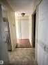 Hallway featuring light-toned tile flooring transitioning to wood-finish flooring - 306 9730 156 Street, Edmonton, AB 