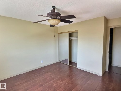 Bedroom featuring wood-finish flooring, a ceiling fan with integrated lighting, and a closet with mirrored sliding doors - 306 9730 156 Street, Edmonton, AB 