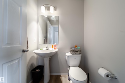 Pedestal sink with chrome faucet, mirror, and an overhead vanity light fixture - 3038 Checknita Way Sw, Edmonton, AB 