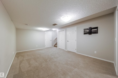Carpeted room featuring light gray walls, multiple white panel doors, and a wall-mounted bracket - 3038 Checknita Way Sw, Edmonton, AB 