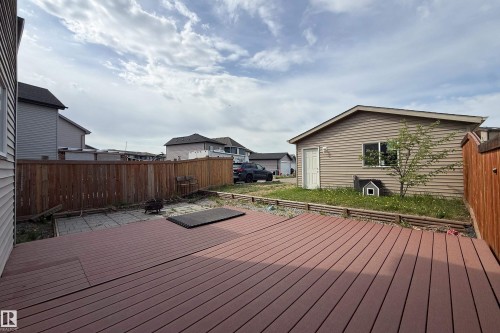 Expansive rear yard featuring a composite deck, a paved patio area, and a large detached garage - 3038 Checknita Way Sw, Edmonton, AB 