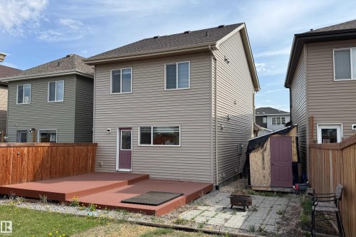 Two-story residence featuring light-toned horizontal siding, a multi-level deck, and a wooden privacy fence - 3038 Checknita Way Sw, Edmonton, AB 