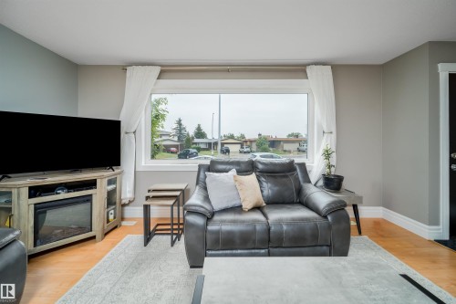 Bright living area featuring wood-finish flooring and a large picture window - 8512 142A Avenue, Edmonton, AB 