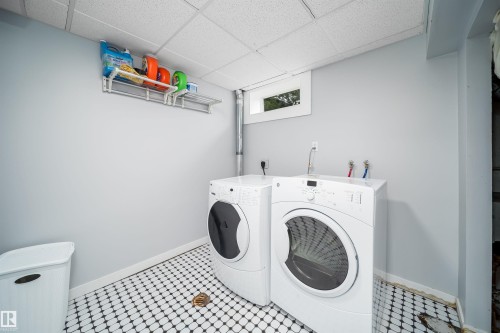 Laundry area featuring black and white mosaic tile flooring, light gray walls, a window, and a drop ceiling - 8512 142A Avenue, Edmonton, AB 