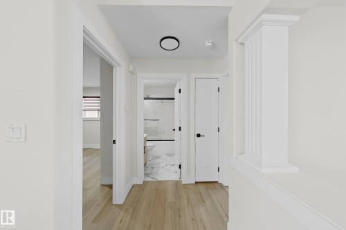 Light wood-finish flooring throughout, bright white walls, and contemporary black hardware on interior doors - 6144 166 Avenue, Edmonton, AB 