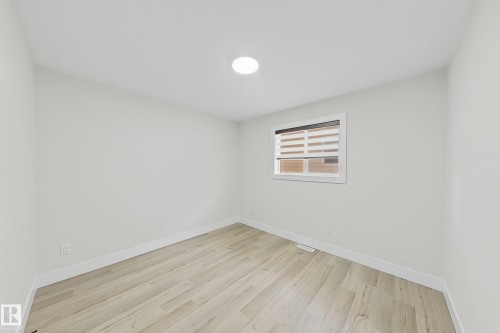 Bright room featuring light wood-finish flooring, white baseboards, and a single window with horizontal blinds - 6144 166 Avenue, Edmonton, AB 