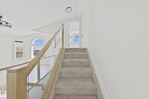Carpeted staircase with light wood-finish and glass railing - 6144 166 Avenue, Edmonton, AB 