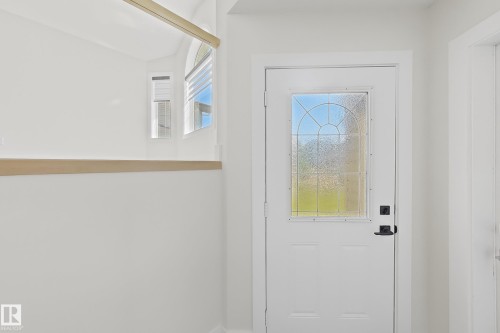 Entry door with decorative glass insert, black hardware, and light wood accent trim - 6144 166 Avenue, Edmonton, AB 