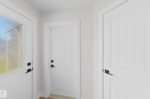 Entryway featuring a white door with decorative glass, a paneled interior door, and matte black hardware throughout - 6144 166 Avenue, Edmonton, AB 