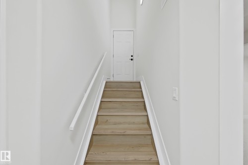 Staircase featuring wood-finish treads, a white handrail, and white risers - 6144 166 Avenue, Edmonton, AB 