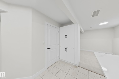 Built-in white cabinetry with black hardware, white paneled interior door, tiled flooring, and a round ceiling light fixture - 6144 166 Avenue, Edmonton, AB 