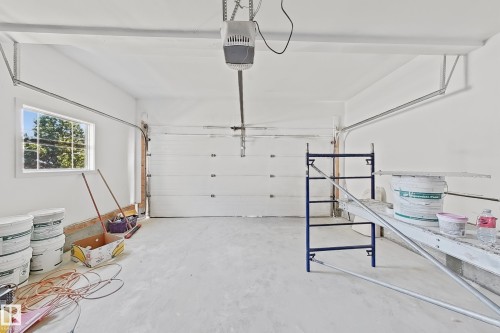 Spacious garage with a sectional garage door, high ceilings, a single window, and a concrete floor - 6144 166 Avenue, Edmonton, AB 