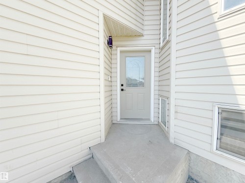 Entryway featuring light-toned horizontal siding, a glass-paneled entry door, and a concrete stoop - 6144 166 Avenue, Edmonton, AB 