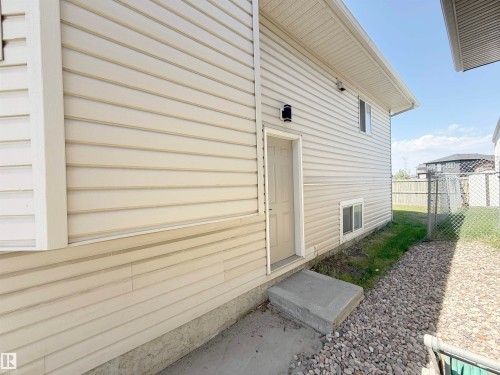 Exterior wall with horizontal siding, featuring a side entry door with concrete steps - 6144 166 Avenue, Edmonton, AB 
