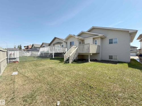 Expansive backyard featuring a raised wooden deck with staircase, chain-link and wood fences, and a detached storage shed - 6144 166 Avenue, Edmonton, AB 