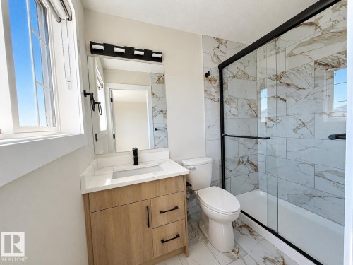 Bathroom with a light wood-finish vanity, white countertop, and rectangular sink - 6144 166 Avenue, Edmonton, AB 