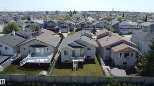 Rear exterior featuring a spacious wooden deck with white railing, a fenced backyard, and mature trees beyond the property line - 6144 166 Avenue, Edmonton, AB 