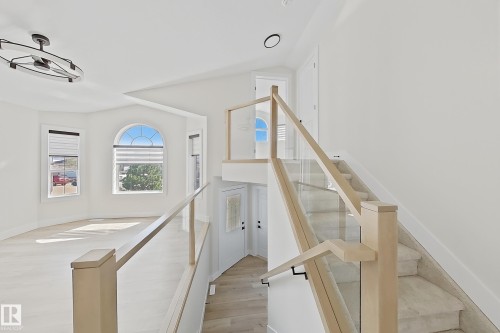 Modern interior featuring a grand staircase with glass railings and wood newel posts - 6144 166 Avenue, Edmonton, AB 