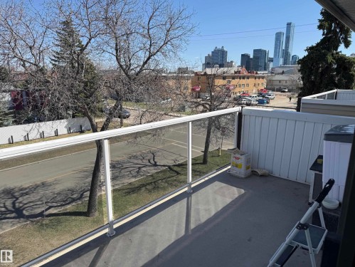 Balcony featuring a glass railing, composite decking, and a cityscape backdrop - 304 10604 110 Avenue, Edmonton, AB 