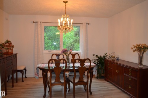 Spacious dining area featuring wood-finish flooring, a contemporary chandelier, and a large window - 68 Marlboro Road, Edmonton, AB 