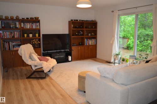 Living area featuring wood-finish flooring, built-in shelving units, and sliding glass doors - 68 Marlboro Road, Edmonton, AB 