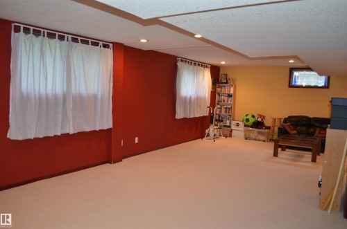 Spacious room featuring neutral carpet flooring, recessed lighting, and a drop ceiling with decorative soffit - 68 Marlboro Road, Edmonton, AB 