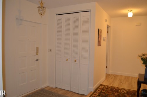 Entryway featuring a paneled door, louvered bi-fold closet doors, wood-finish flooring, and an ornate ceiling fixture - 68 Marlboro Road, Edmonton, AB 