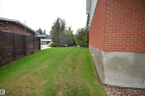Expansive side yard featuring a manicured lawn, established landscaping, and a privacy fence - 68 Marlboro Road, Edmonton, AB 