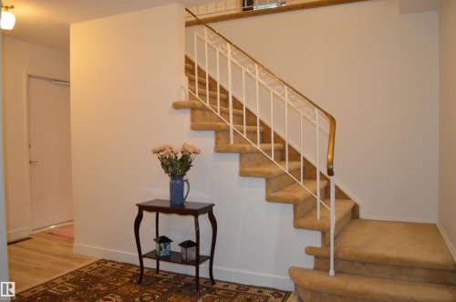 Staircase with carpeted treads and risers, featuring a white wrought-iron railing with a brass-toned top rail - 68 Marlboro Road, Edmonton, AB 