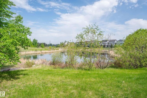 Expansive natural landscape featuring a serene pond surrounded by lush greenery and distant residential structures - 40 604 62 Street, Edmonton, AB 