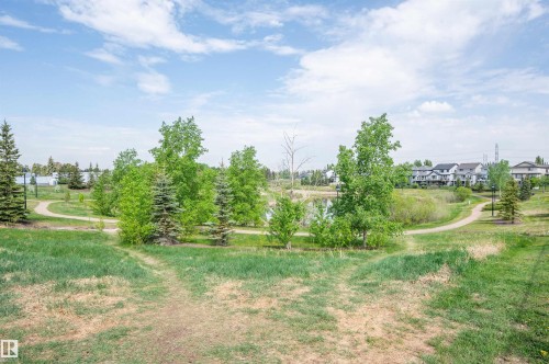 Expansive green space featuring mature trees, a tranquil pond, and paved walking paths - 40 604 62 Street, Edmonton, AB 