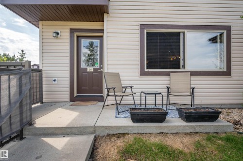 Inviting front entrance with a concrete patio, featuring a brown paneled door with a glass insert and an exterior wall lantern - 40 604 62 Street, Edmonton, AB 