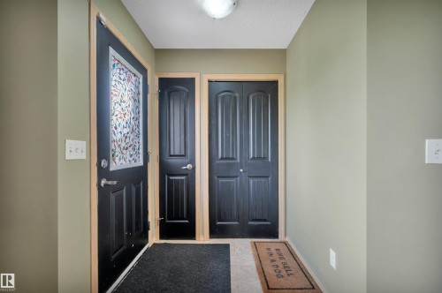Entryway featuring a black paneled door with decorative glass insert, light-toned wall paint, and light wood trim - 40 604 62 Street, Edmonton, AB 