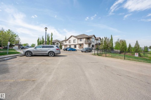 Property exterior featuring a multi-level design with balconies, mature trees, and a paved parking area - 40 604 62 Street, Edmonton, AB 