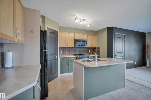 Kitchen featuring a central island with an undermount double basin sink and gooseneck faucet - 40 604 62 Street, Edmonton, AB 