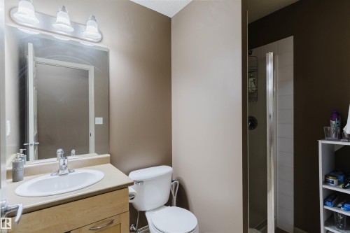 Full bathroom featuring a single vanity with wood-finish cabinetry, a white oval sink, and a light-toned countertop - 1-405 4245 139 Avenue, Edmonton, AB 