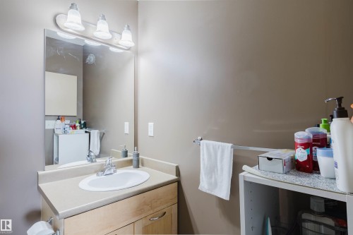 Bathroom vanity with an integrated sink, laminate countertop, and wood-finish cabinetry - 1-405 4245 139 Avenue, Edmonton, AB 