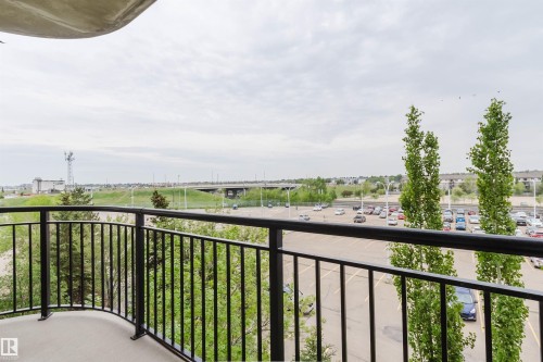 Private balcony with black iron railing overlooking a parking area and distant infrastructure - 1-405 4245 139 Avenue, Edmonton, AB 
