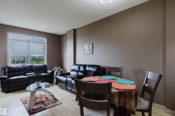 Open-concept living and dining area featuring light wood-finish flooring, neutral wall tones, and a large window providing ample natural light - 